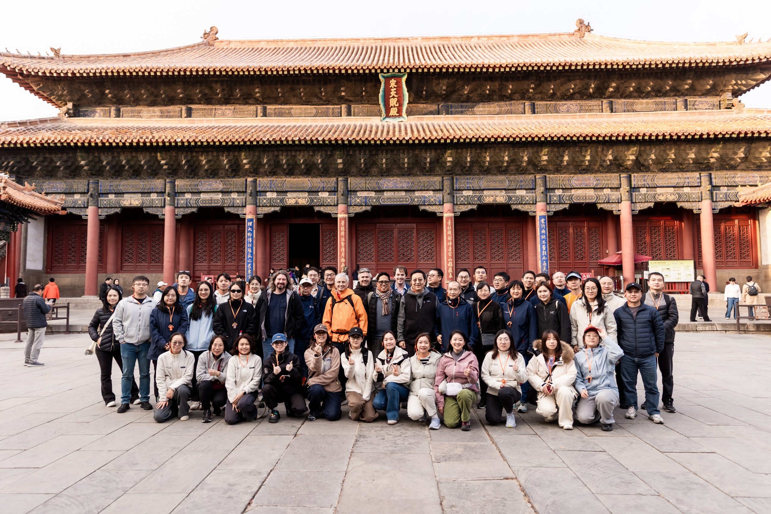 A large group of Structure Therapeutics employees poses for a photo on a paved stone courtyard in front of a grand traditional Chinese building.